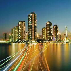 Illuminated modern buildings in city against sky at night