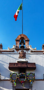 Low angle view of sculptures on building against blue sky