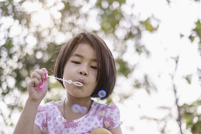 Girl blowing bubbles in park