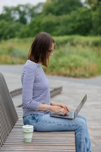 Young and confident woman blogger or freelancer with laptop working in a park or public place