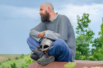 Side view of man in medieval viking clothing. metal helmet and chain mail. blurred background.