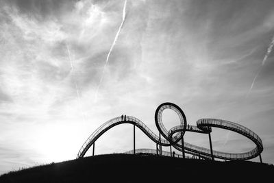 Rollercoaster against cloudy sky at amusement park