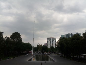 Road by buildings in city against sky