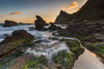 Scenic view of rocks in sea against sky during sunset