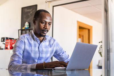 Serious businessman using laptop at table in coworking office