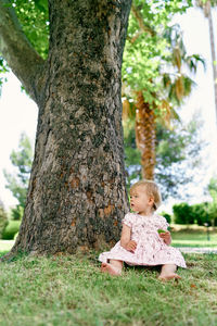 Boy sitting on tree trunk