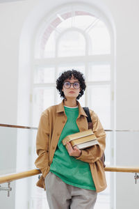 Portrait of young woman standing against wall