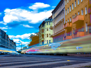 Cars on street by buildings against sky in city