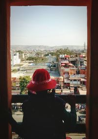 Rear view of woman standing against window in city
