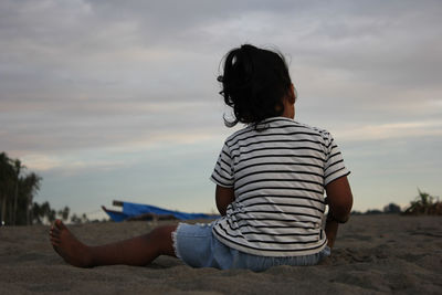 Rear view of woman sitting on land against sky