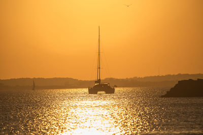 Sailboat sailing on sea against sky during sunset