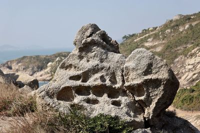 Close-up of rock on land against sky