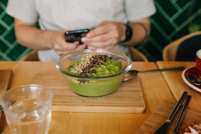 Midsection of man holding glass bowl on table