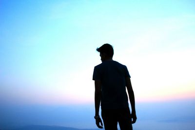 Rear view of silhouette man walking against clear sky