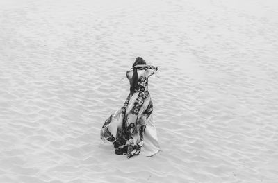 Rear view of woman standing at sandy beach