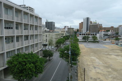 Road by buildings in city against sky