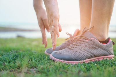 Low section of woman wearing shoes on grass