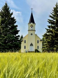 Church on field by building against sky