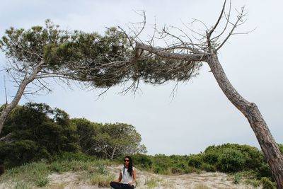 Woman relaxing by tree at beach