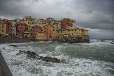 Buildings by sea against sky