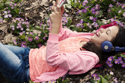 Girl using mobile phone while lying on field at park