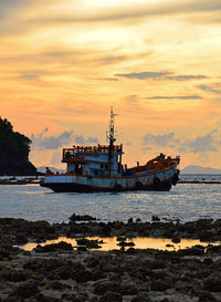 Ship on sea against orange sky during sunset
