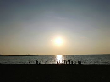 Silhouette people on beach against sky during sunset
