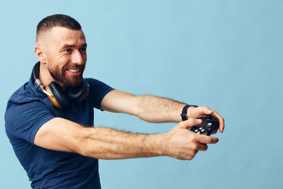 Portrait of young man exercising against blue background
