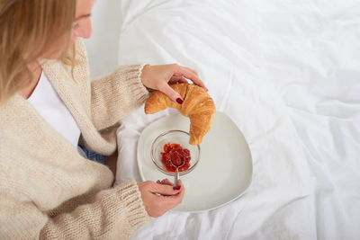 High angle view of woman having breakfast on bed at home
