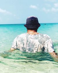 Rear view of young man swimming in sea against sky