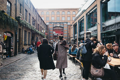 People walking on street amidst buildings in city