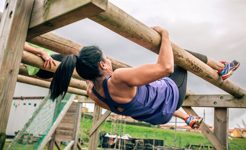 Full length of woman exercising on monkey bars