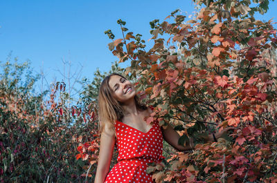Beautiful girl in a red dress among the woods. snow-white smile.blue sky. person