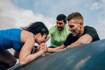 Woman climbing on rooftop against sky