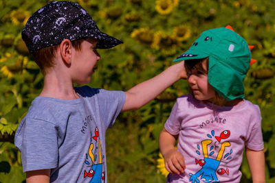 Boy and girl with baseball caps sitting outdoors 