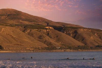 View of sea by mountain against sky during sunset