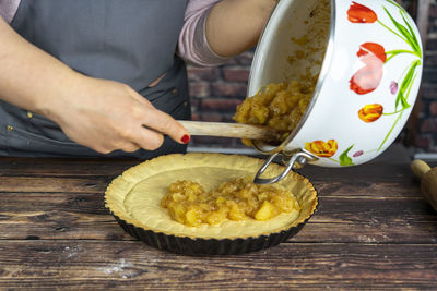 Women preparing delicious apple tart or pie .spreading the cooked candied apple over the dough