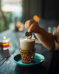 Midsection of person holding coffee cup on table