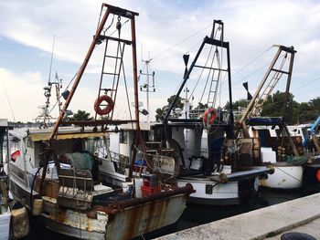 Boats moored at harbor against sky