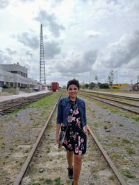 Portrait of man standing on railroad track against sky