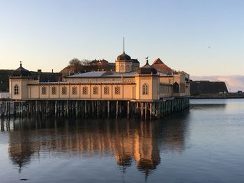 Buildings by river against clear sky