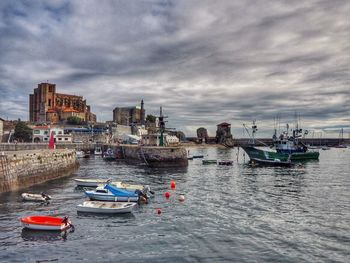 Boats moored in sea against sky in city