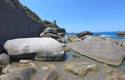 Rocks on beach against clear blue sky