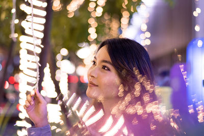 Close-up of young woman amidst illuminated lights