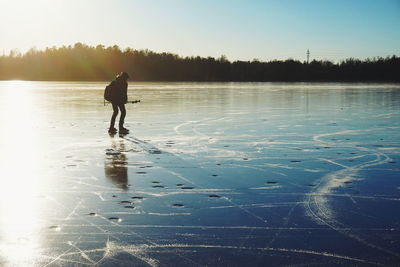 Silhouette man on lake against sky