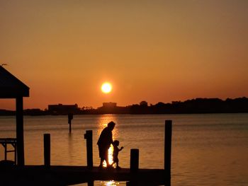 Silhouette people standing on beach against sky during sunset