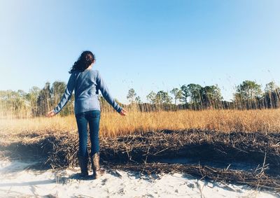 Full length of woman standing on field against clear sky