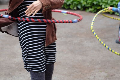Midsection of woman with hula hoop standing on footpath