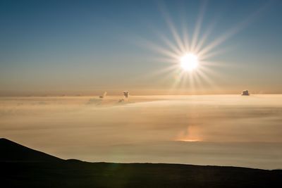 Sun shining through clouds over mountain