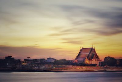 River amidst buildings against sky during sunset